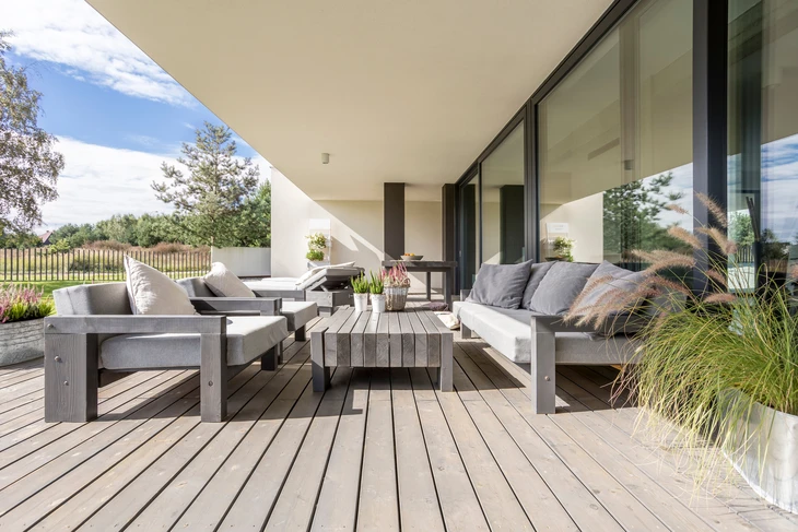 Terrasse couverte d'une maison contemporaine avec salon de jardin en résine tressée