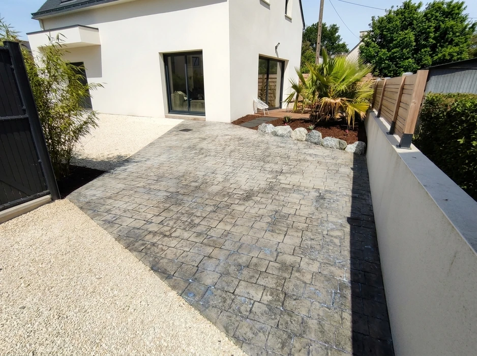 Allée de jardin pavée en pavés autobloquants ton pierre grise, bordure noire, dallage irrégulier type opus romain