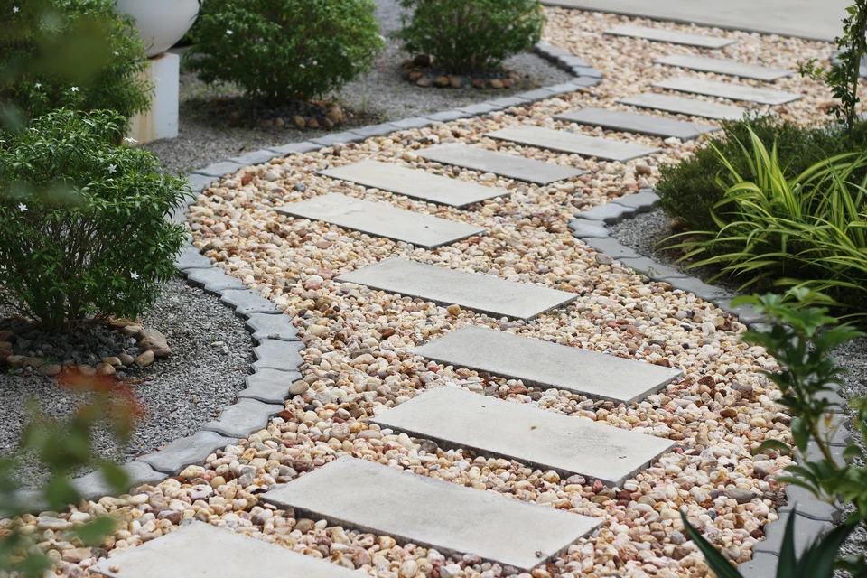 Allée de jardin pavée en briques avec motif en chevrons, bordée de pelouse verte et plantations paysagères variées