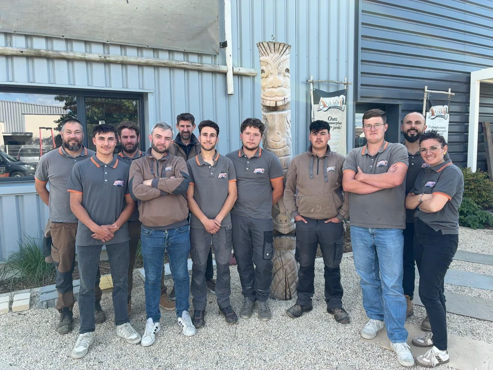 Homme en tenue de travail utilisant une barre à mine pour creuser une tranchée le long d'un mur de soutènement en blocs de béton préfabriqués